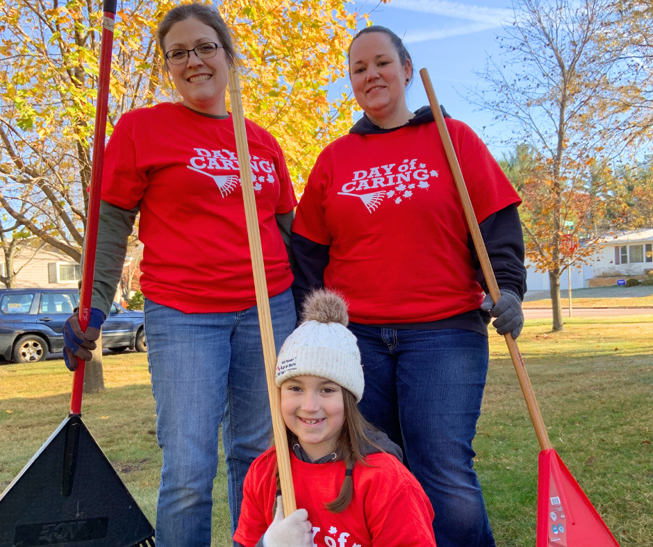 Volunteers smiling and holding rakes from Day of Caring 2024