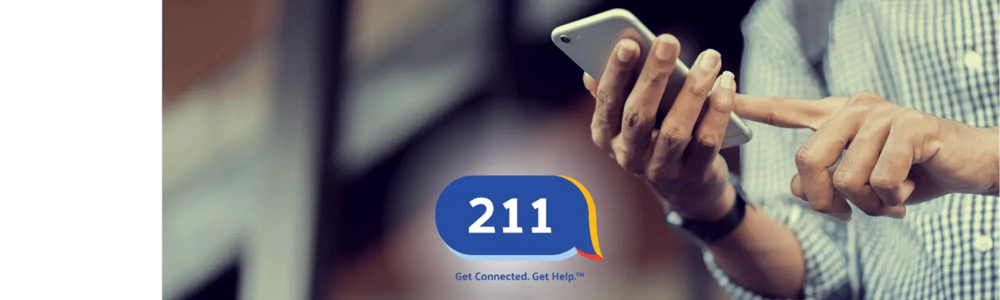 Photo of a man's hands holding a smartphone and the 211 logo.